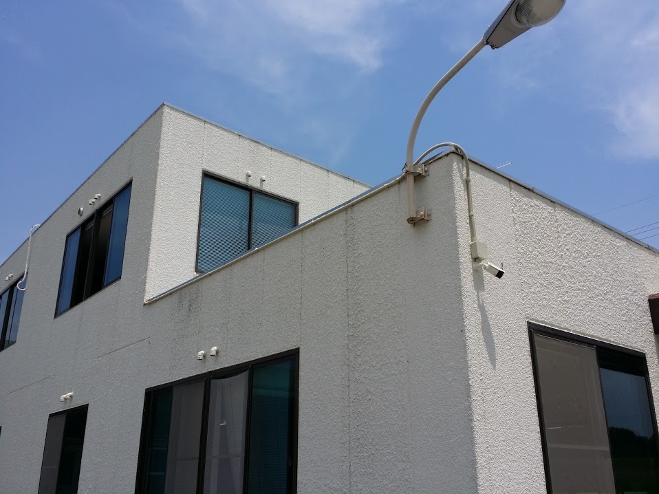 事業所の外壁から出入口を監視する防犯カメラ